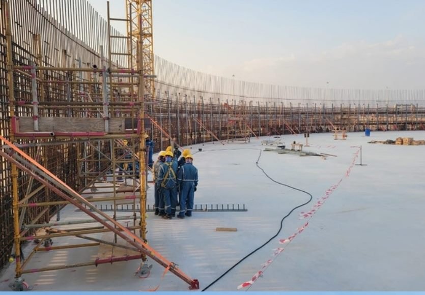 Site crew in hardhats on a concrete slab with scaffolding