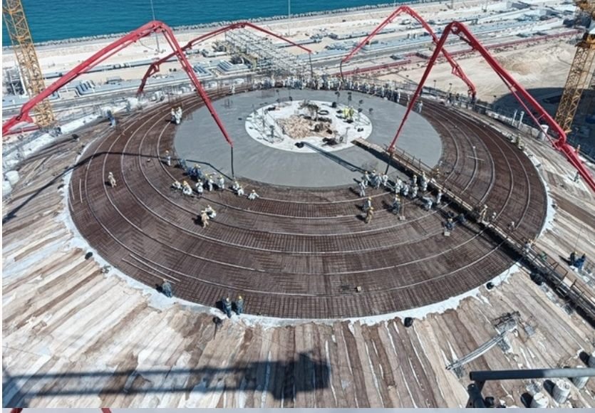 Aerial view of a large-scale circular concrete pour with pump booms and site crew