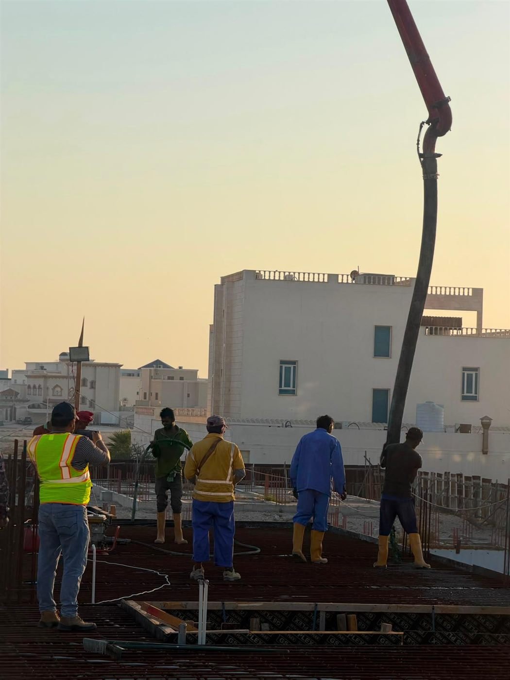 Concrete pump boom against the evening sky at a Doha site